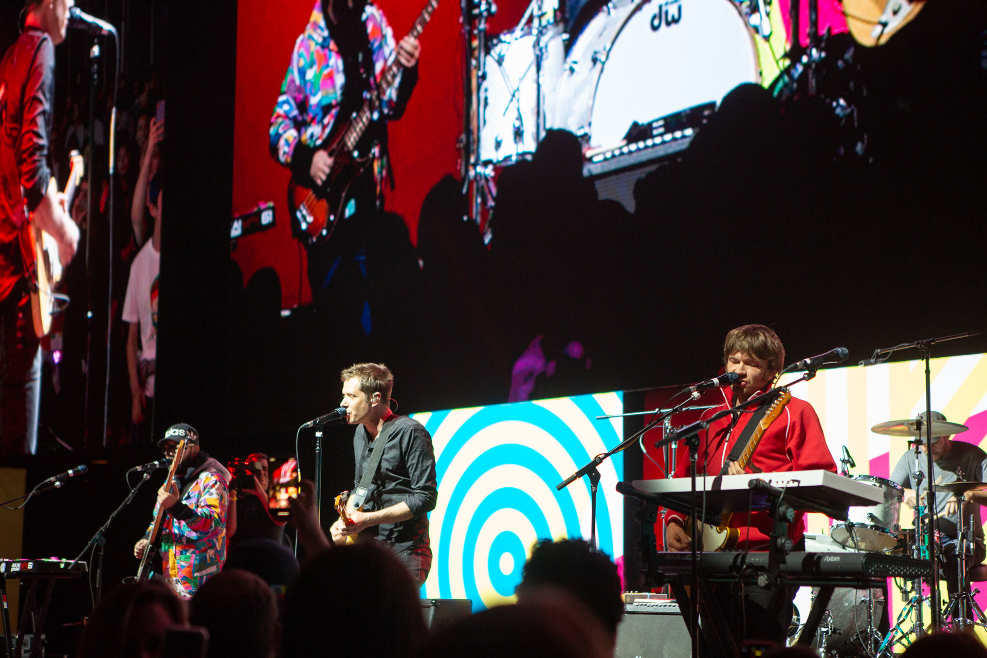 Live band performing on stage with colorful LED backdrop and IMAG screens